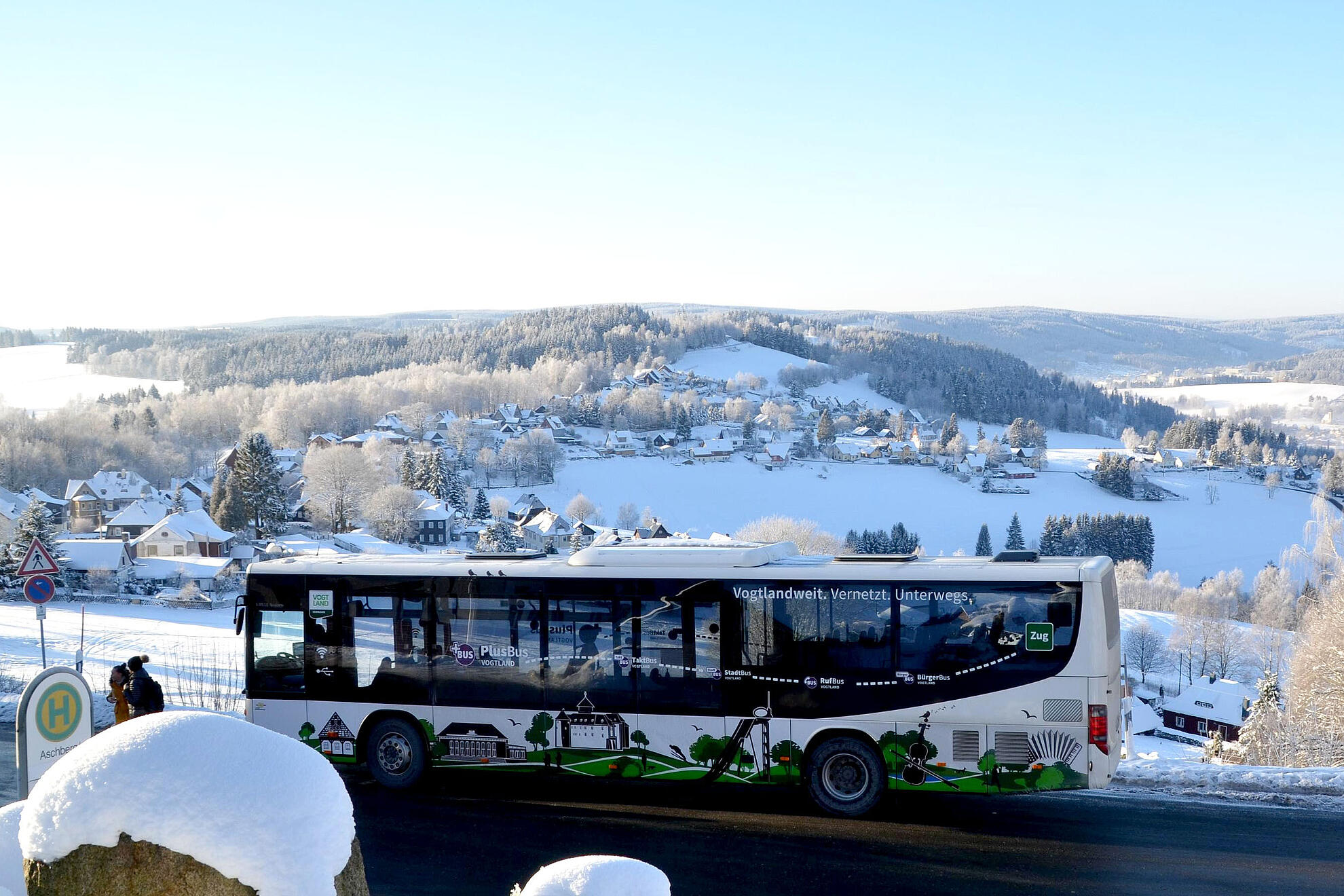 Ein PlusBus fährt im Winter über den verschneiten Aschberg.“