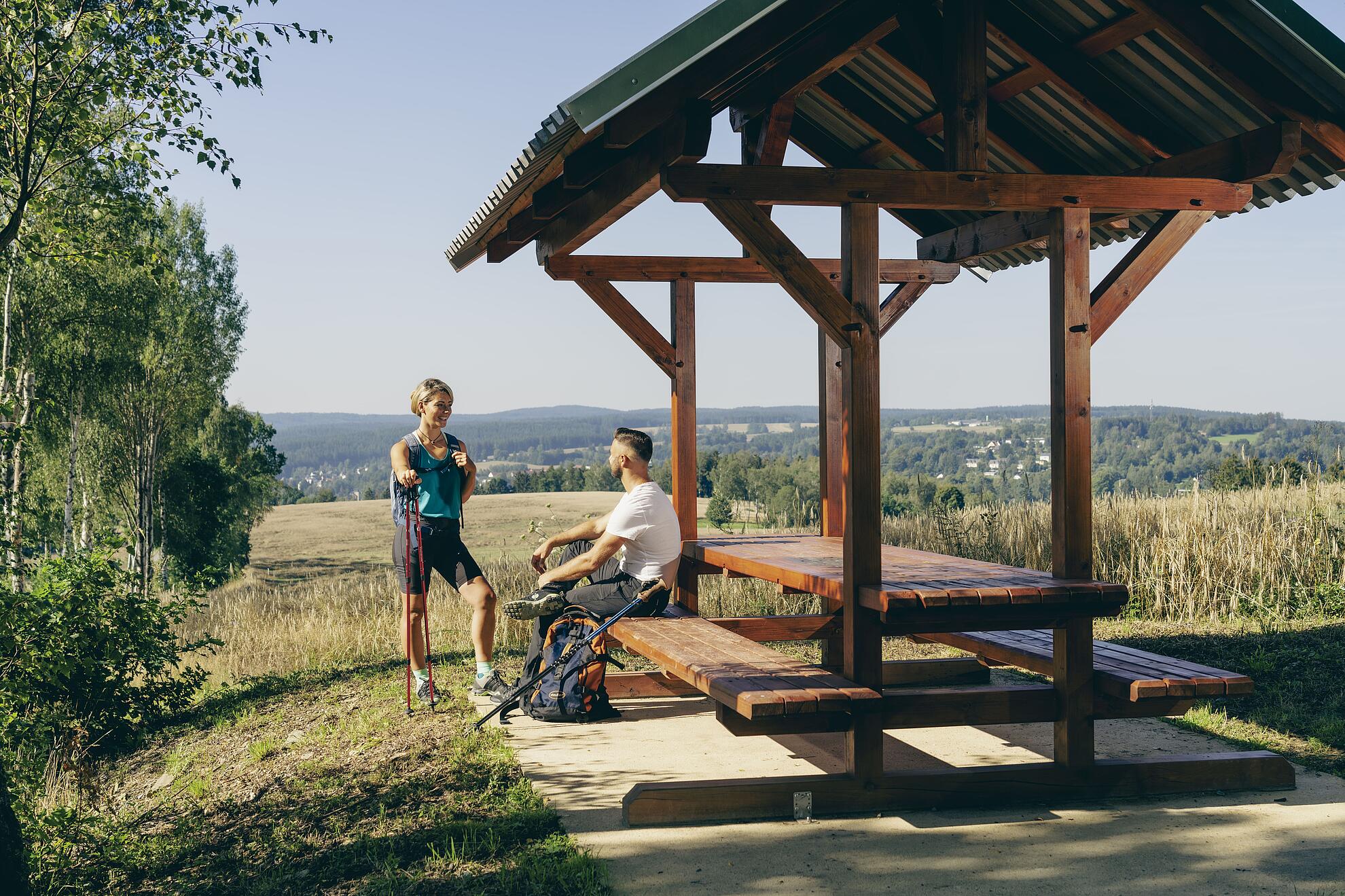Wanderer ruhen sich an einem Rastplatz aus mit Blick auf Adorf