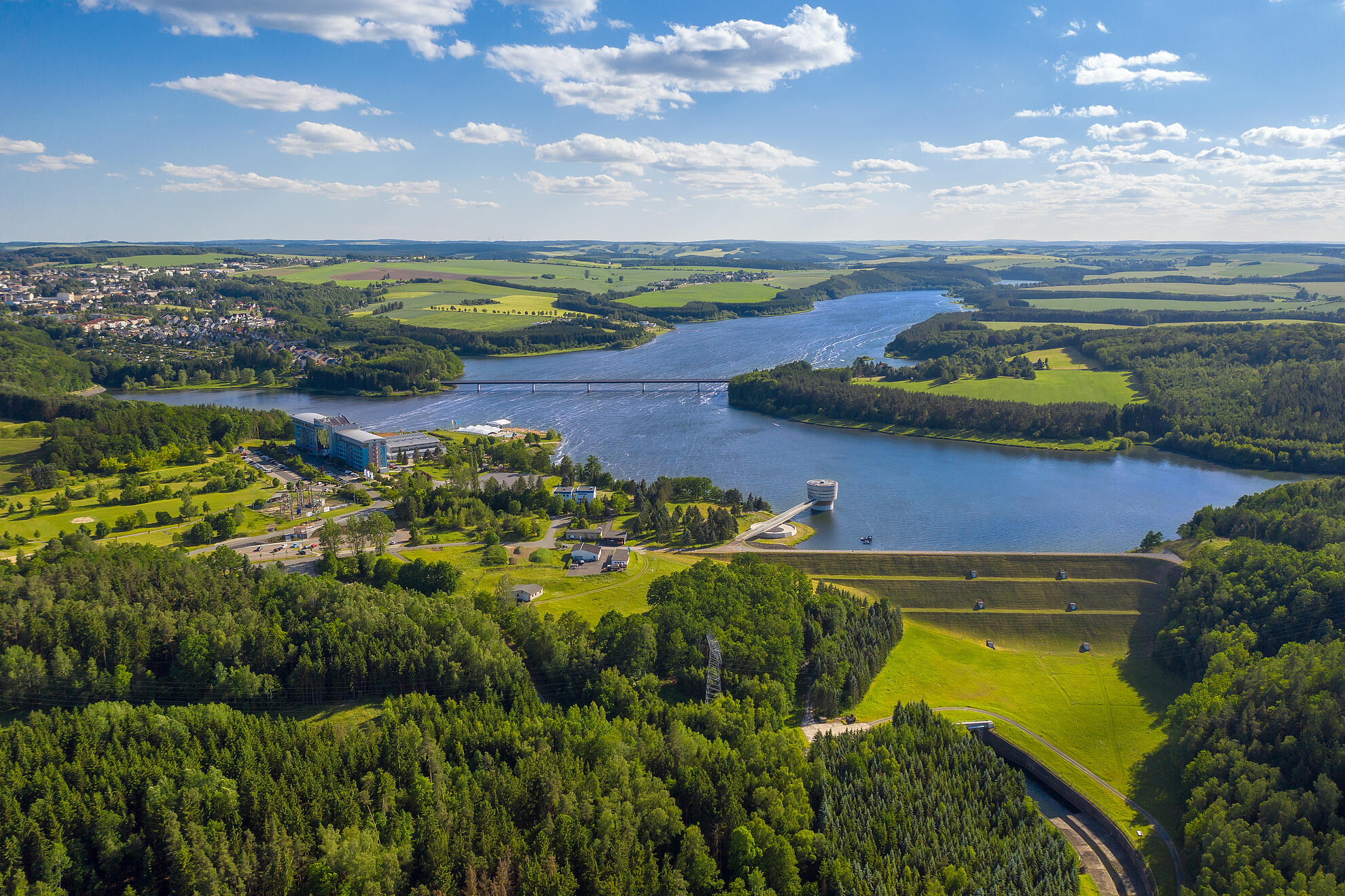 Luftaufnahme des Zeulenrodaer Meers mit weitläufiger Wasserfläche, umliegenden Wäldern, Uferwegen und einzelnen Gebäuden am Seeufer.