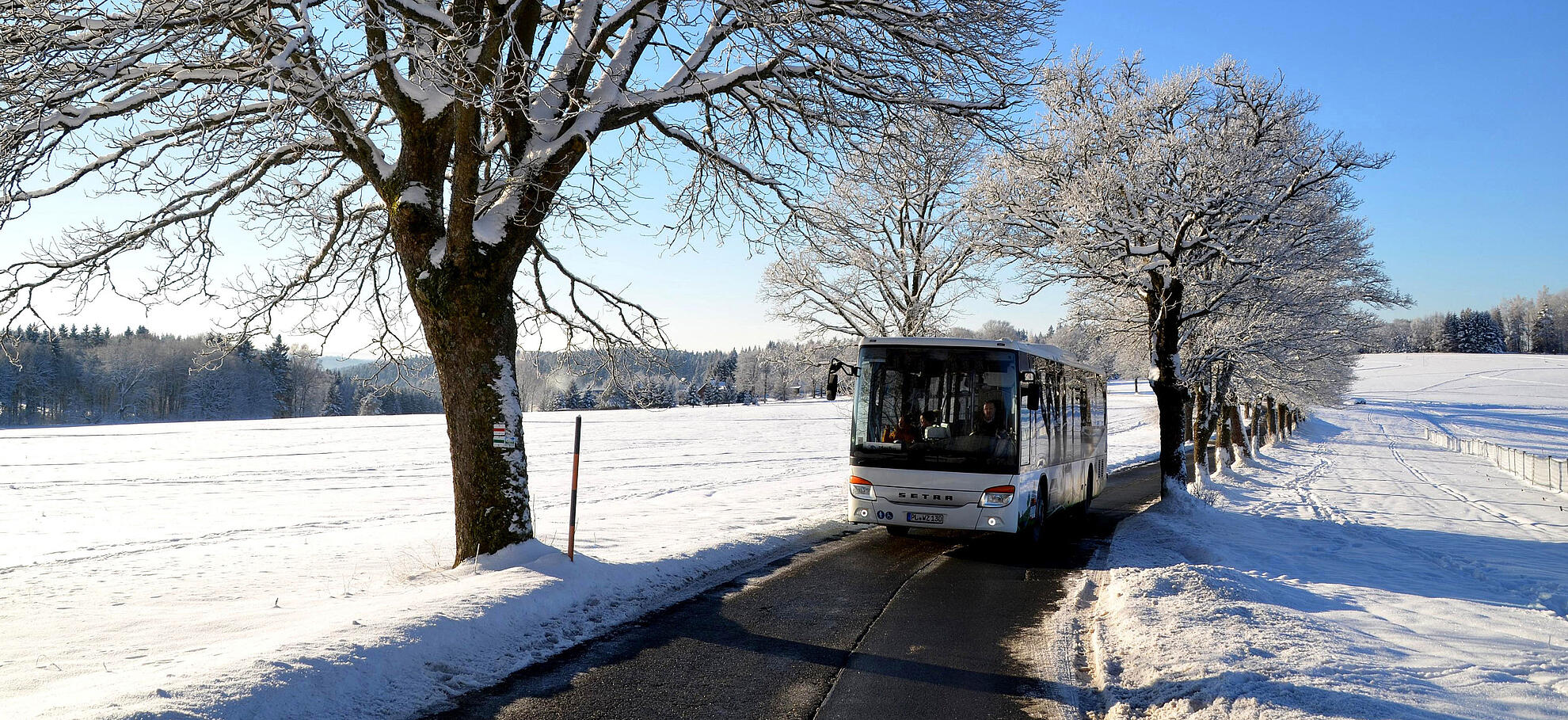Ein PlusBus fährt im Winter über den verschneiten Aschberg.