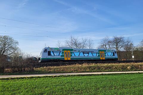 Ein farbenfroher Osterzug fährt durch das frische Grün, unterwegs auf dem Osterpfad im Vogtland.