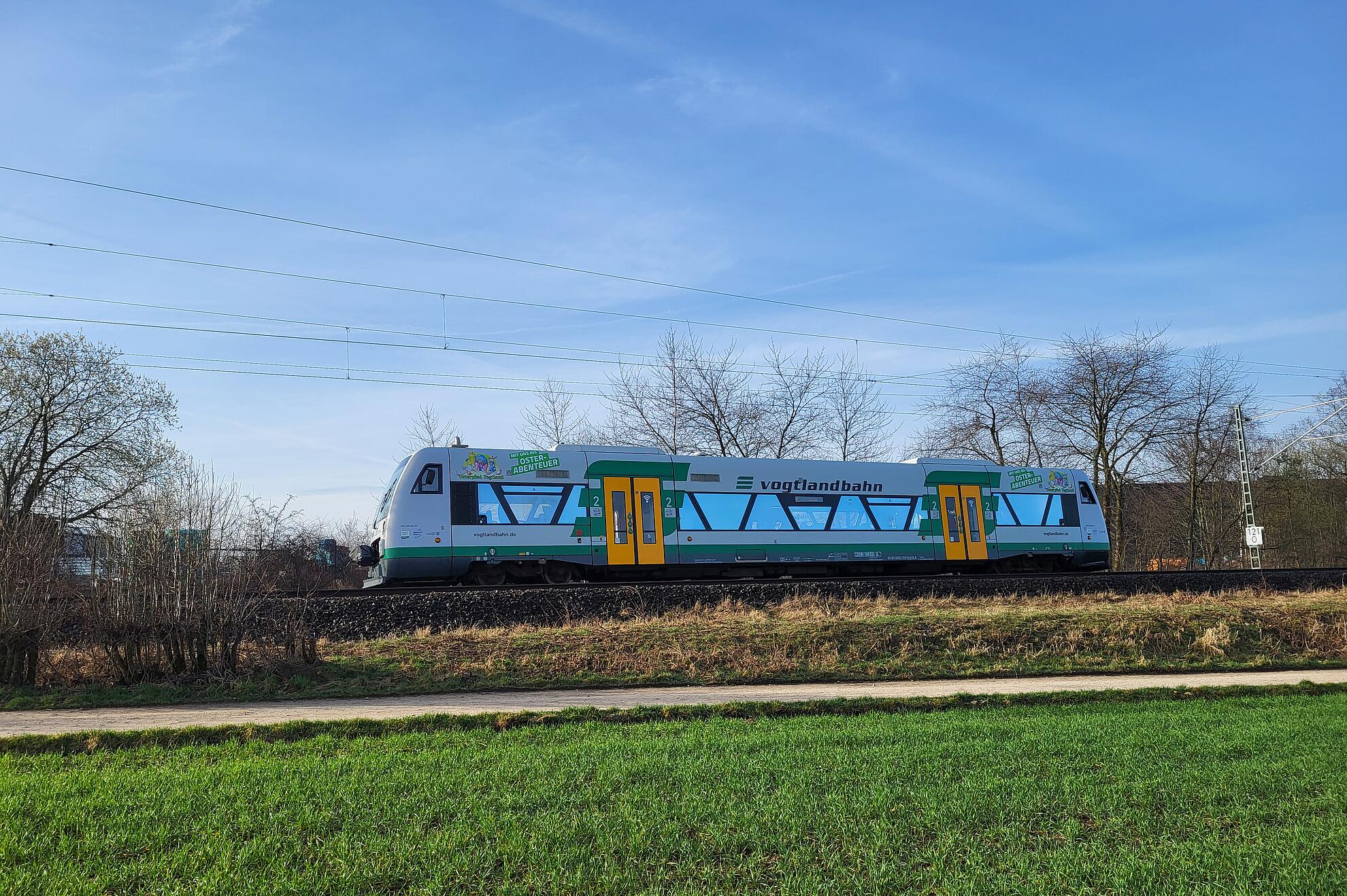 Ein farbenfroher Osterzug fährt durch das frische Grün, unterwegs auf dem Osterpfad im Vogtland.