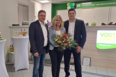 VVV-Geschäftsführer Michael Barth und Landrat Thomas Hennig überreichen Teamleiterin Britta Seidel zum 10‑jährigen Jubiläum der Agentur Plauen einen Blumenstrauß.