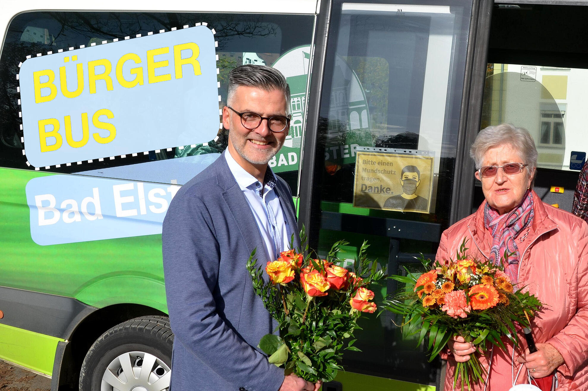Bad Elsters Bürgermeister Olaf Schlott übergibt Blumenan Margarete Ruderisch als 60.000sten Fahrgast.