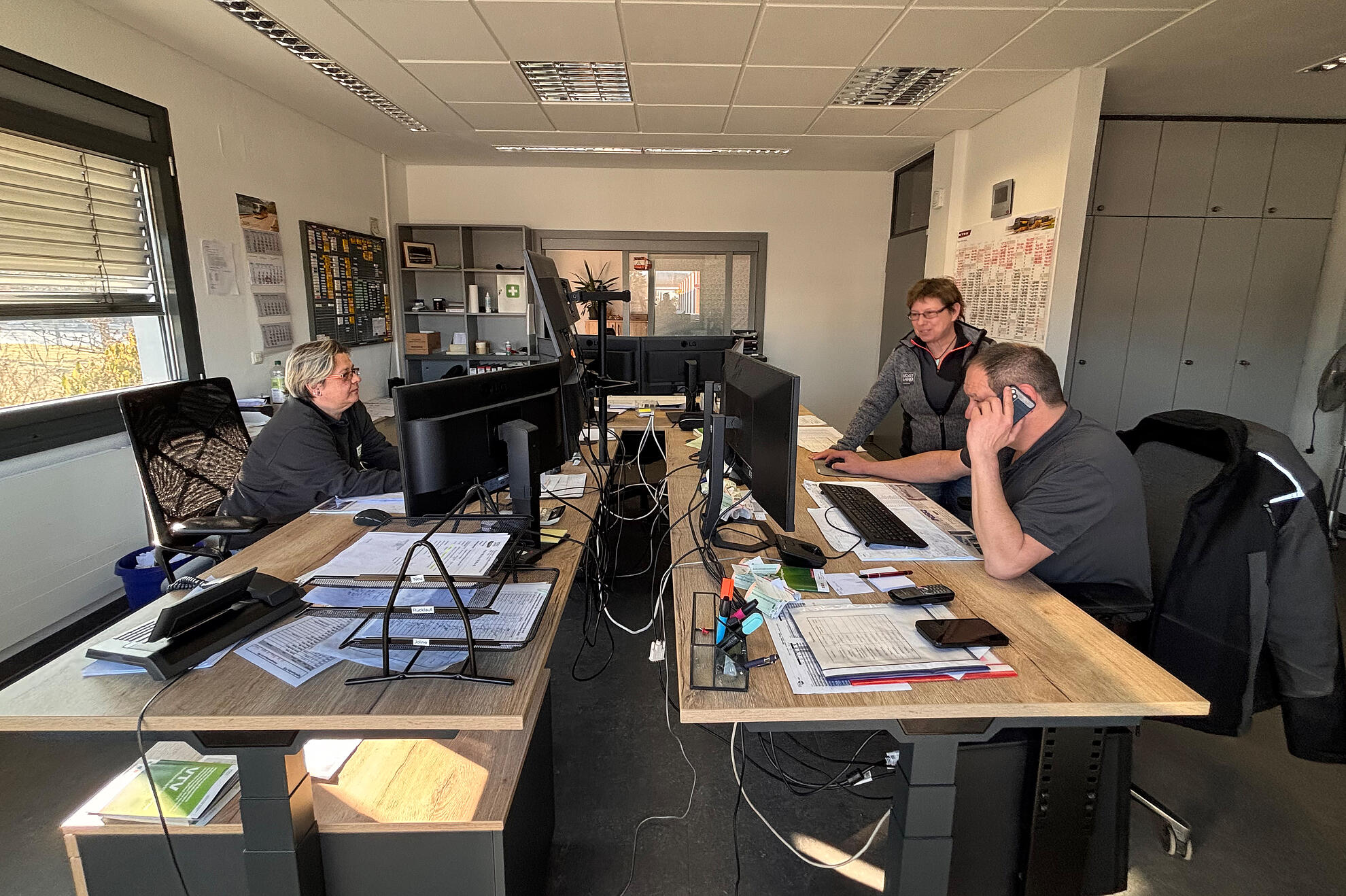 Büro der Einsatzleitung POB mit zwei Tischen; mehrere Personen arbeiten konzentriert an Computern.