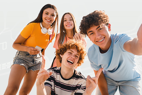 Gruppe aus vier jungen Personen, die lächelnd für ein Foto posieren; Hintergrund mit hellem, abstraktem Linien‑ und Knotenmuster.